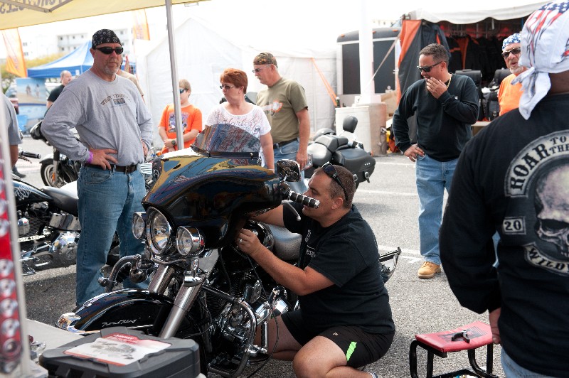 event attendee closely examining motorcycle at vendor tent