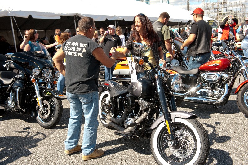 man and woman greeting amongst motorcycles on display in parking lot