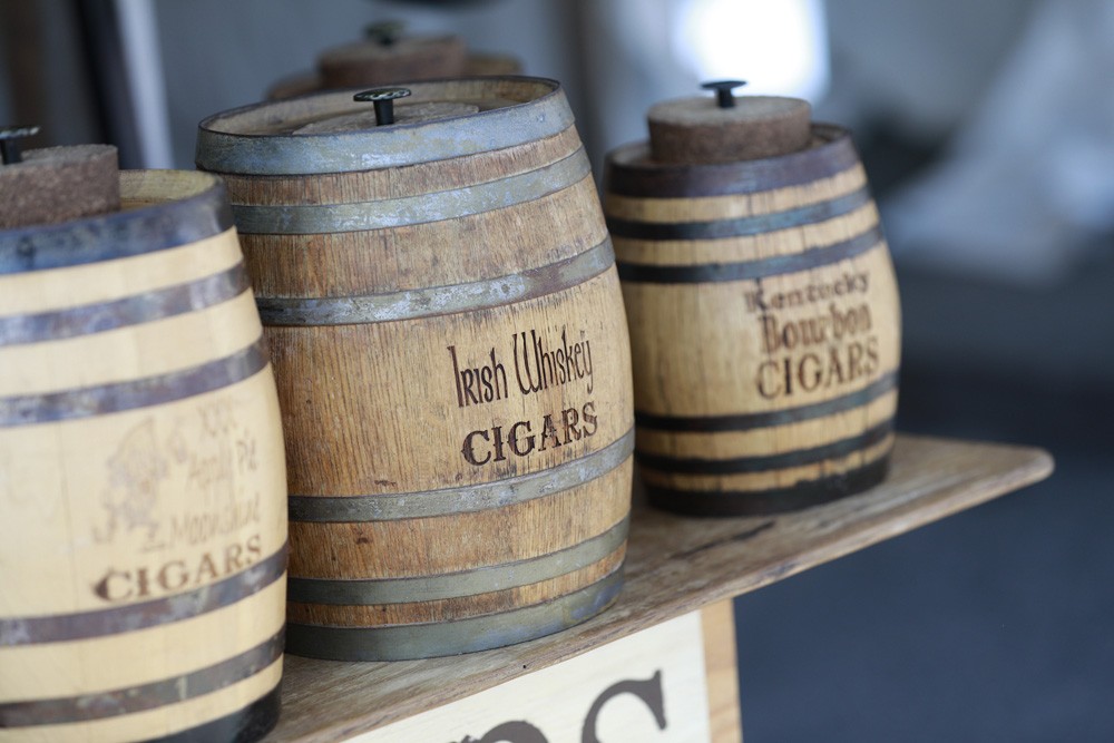close up on barrels imprinted with XXX Apple Pie Moonshine, Irish Whiskey, Kentucky Bourbon and cigars