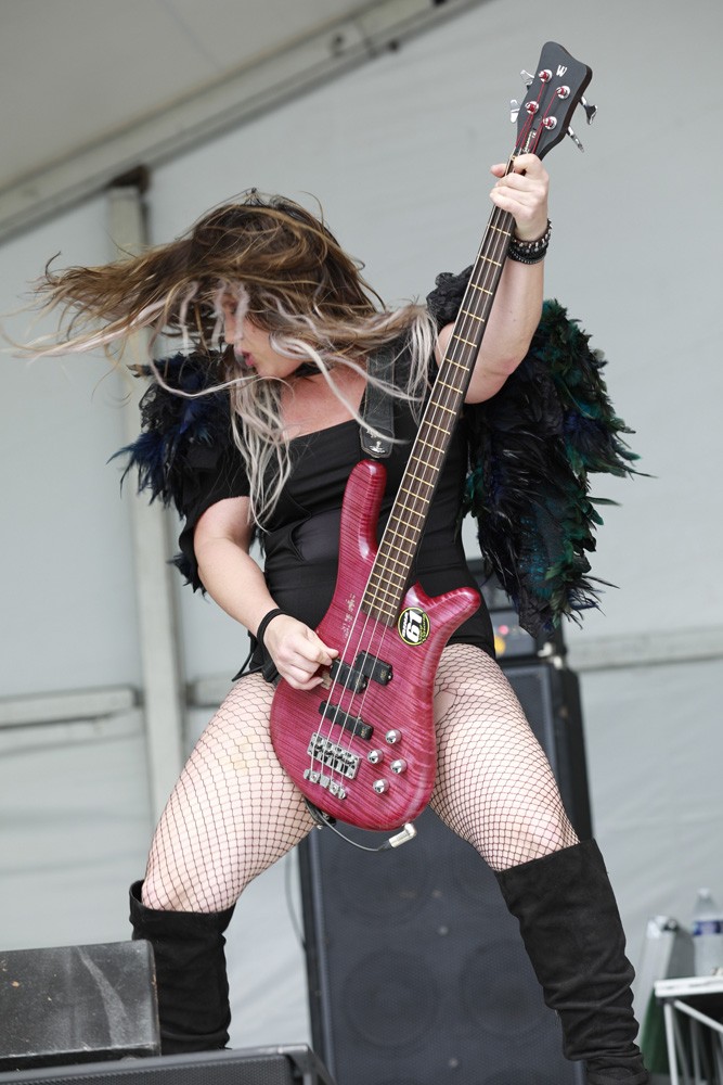 woman intensely playing electric bass guitar on stage
